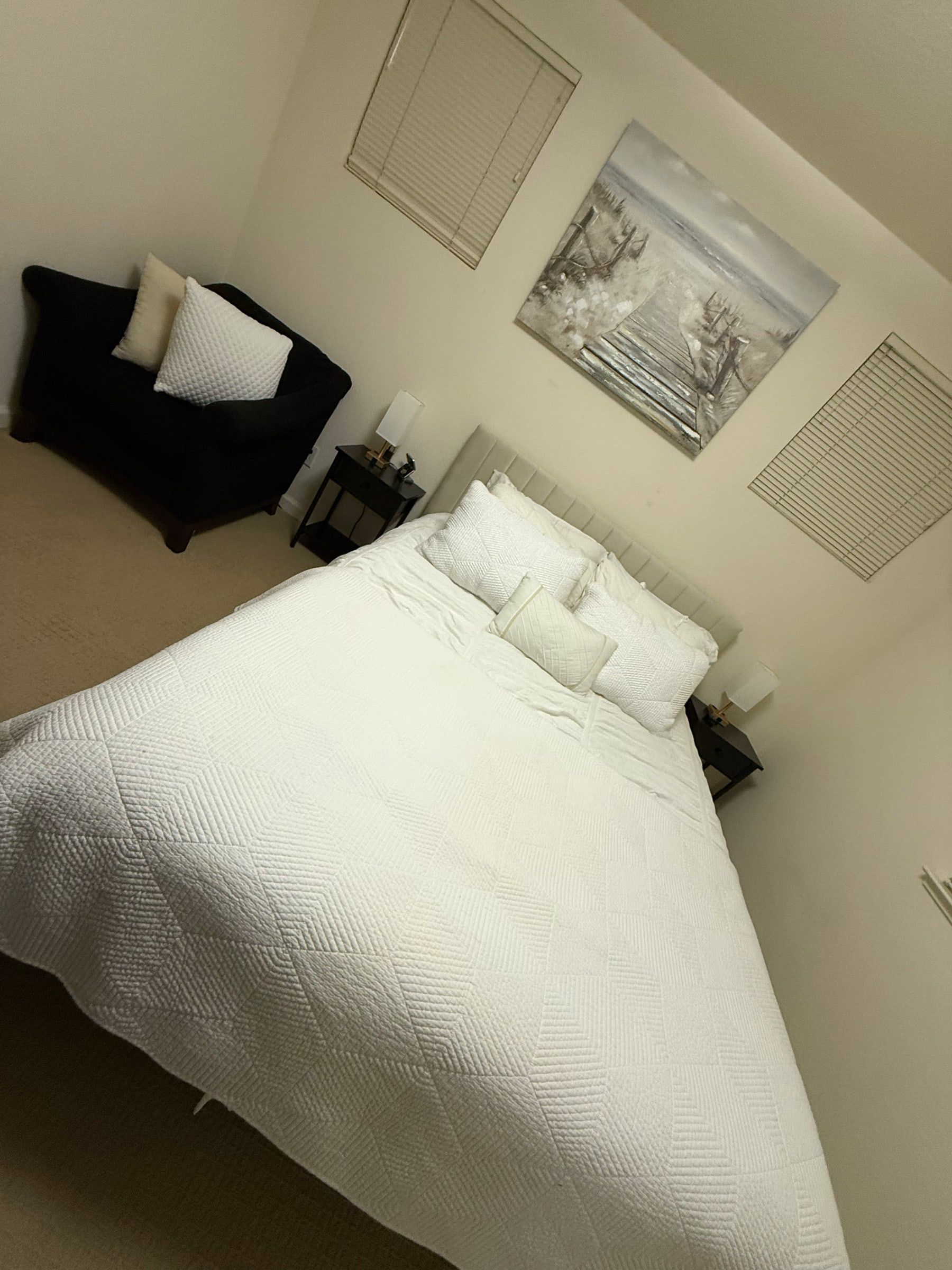 Bed made with crisp white linens in a calm, tidy bedroom